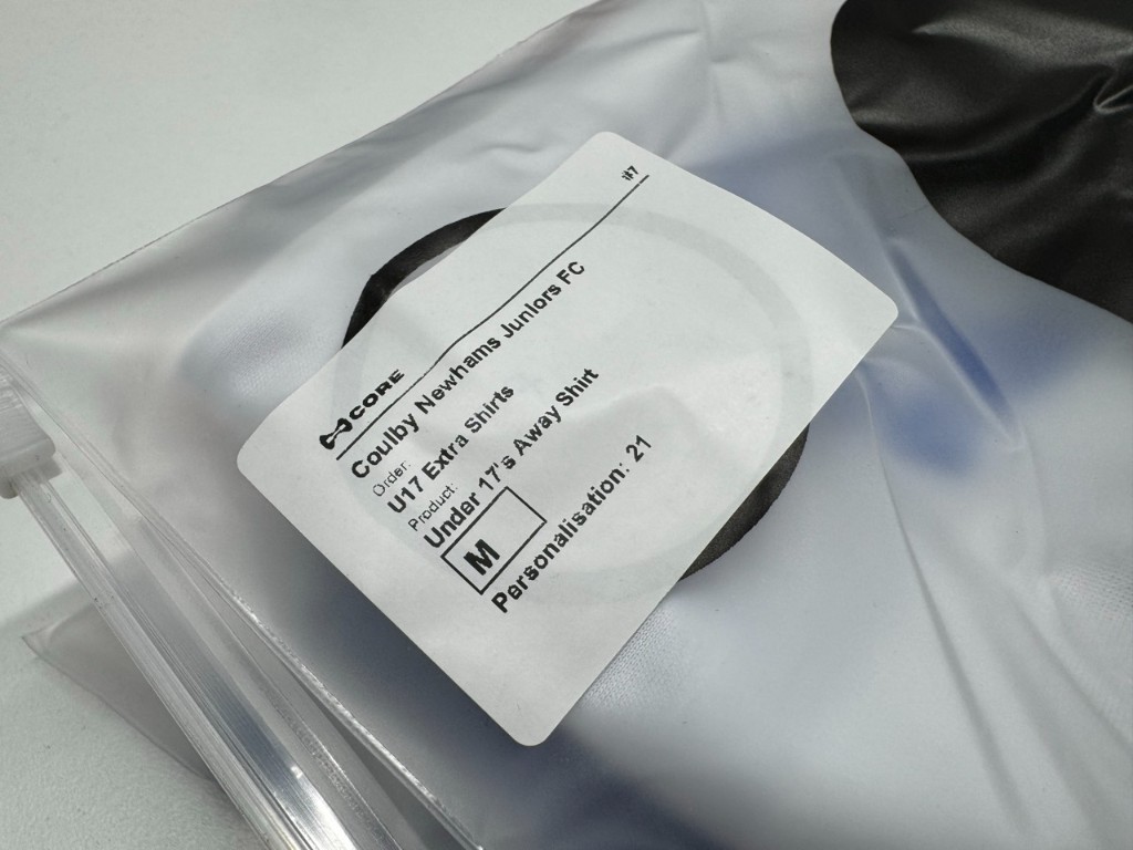 Close-up of a bag label showing Coulby Newhams Juniors FC, Under 17's Away Shirt, size M, and personalisation 21